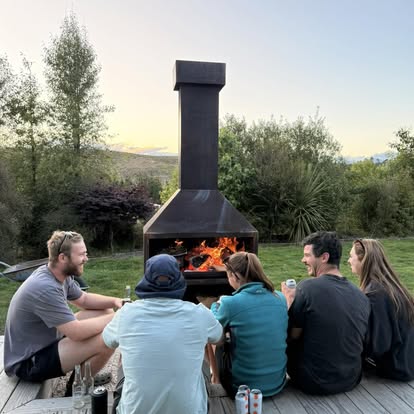 Friends gathered around a lit Lotter outdoor fireplace