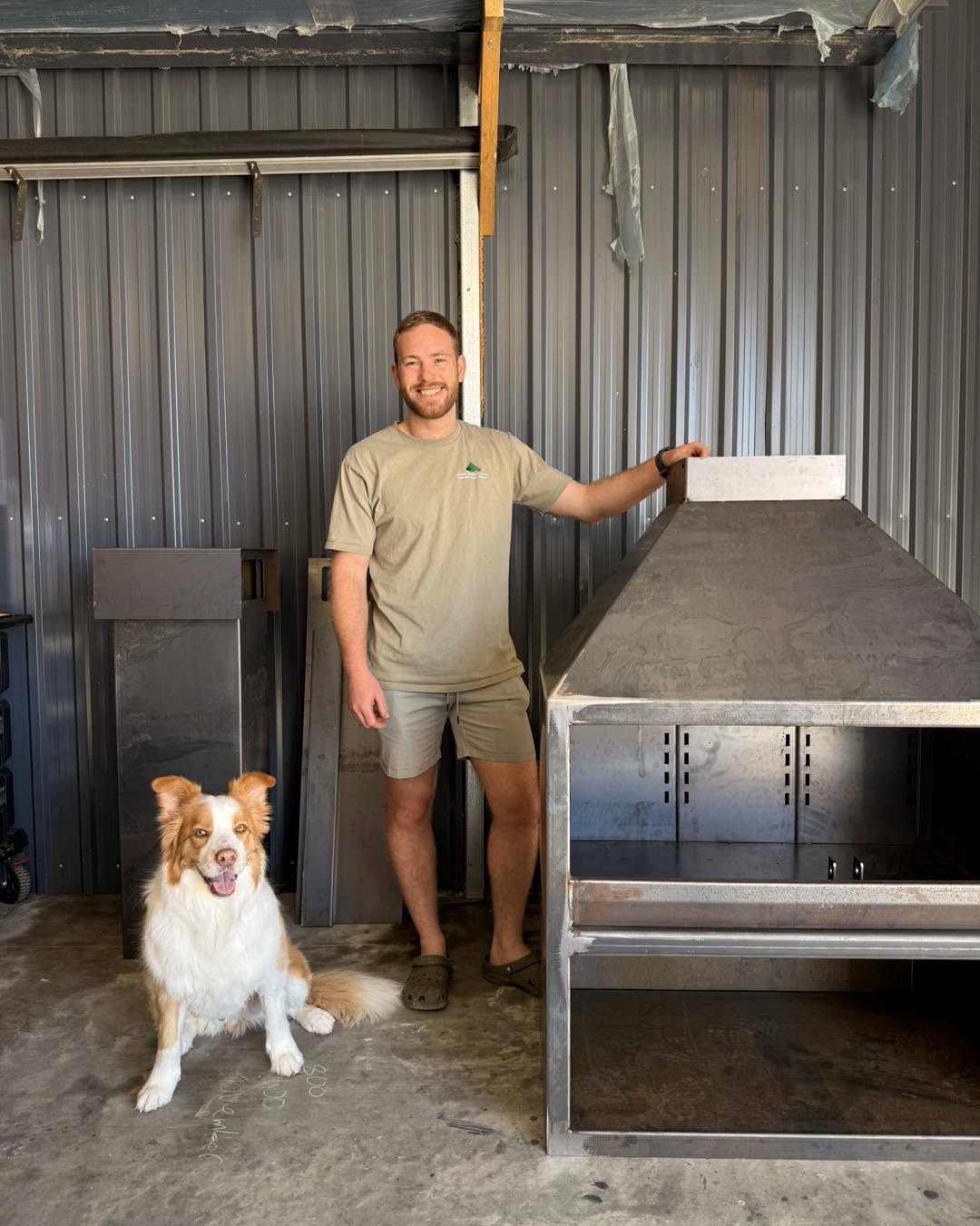 Liam with his dog beside a fireplace in the workshop