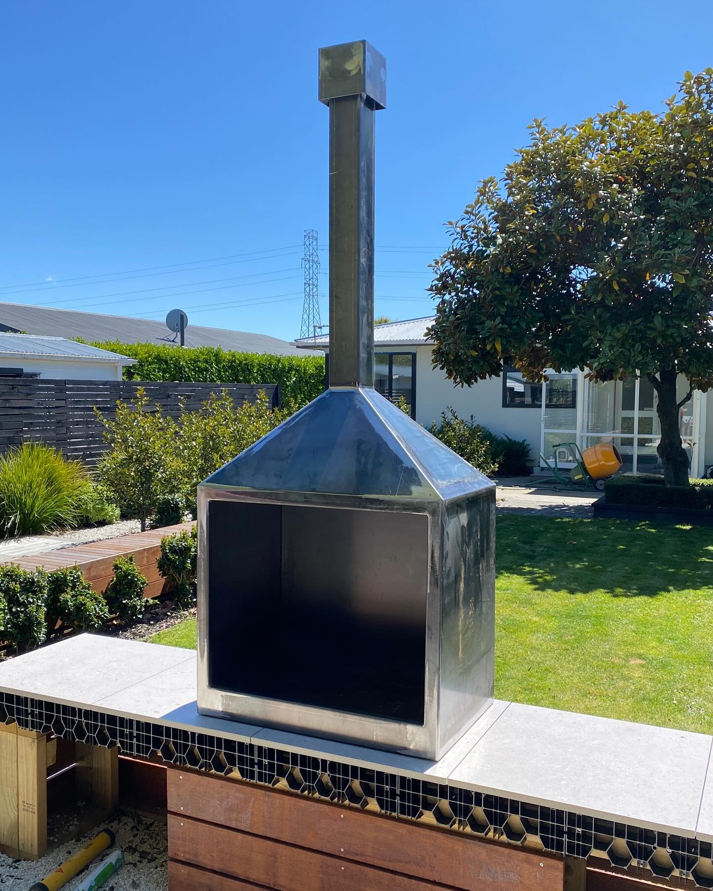 Tall steel outdoor fireplace installed in a garden courtyard